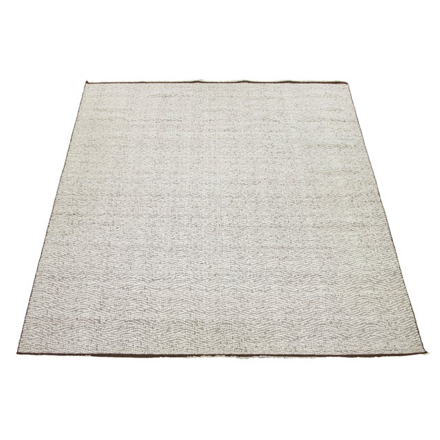 This rug features an Organic modern wool Kilim flatweave design with a brown and ivory base pattern. This rug measures...