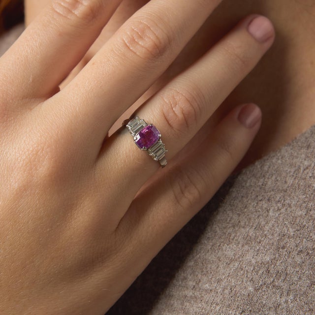 This elegant vintage ring showcases a captivating cushion cut pink sapphire, glowing with a soft yet vibrant hue that...