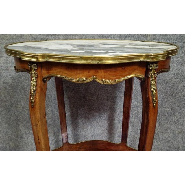 A louis xv style mahogany side table, finely crafted and resting on cabriole legs. the shaped top is made of veined marble...