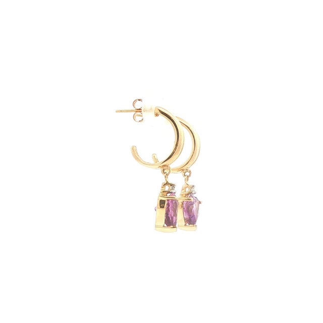 A pair of dangle half hoop earrings crafted from 14k gold. The design features heart-cut purple amethyst stones, exuding...