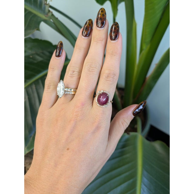 A 12.04-carat red star ruby cabochon sits at the centre of this solid 14K yellow gold ring, framed by twenty-six earth-...