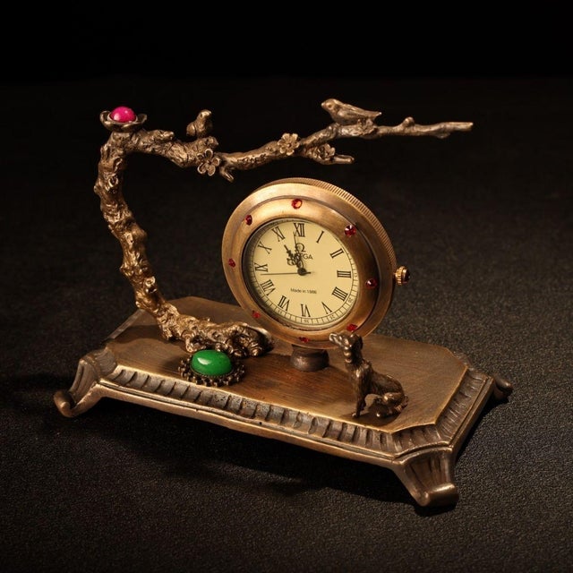 This is a charming vintage bronze table clock featuring an ornate, sculptural design inspired by traditional Asian motifs....