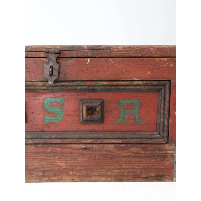 This is an antique carpenter's chest. The painted wooden trunk features metal secured corners and bail handles on the...