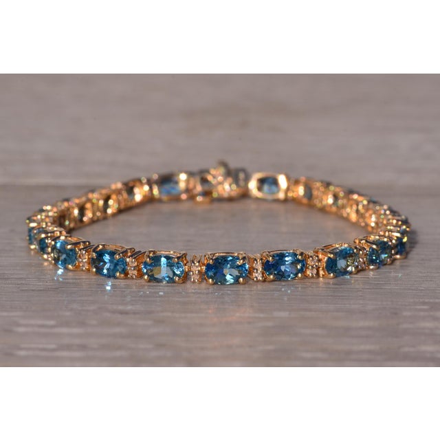 The Londinium: Blue Topaz and Natural Diamond Bracelet in Yellow Gold. The exquisite bracelet showcases stunning 6mm x 4mm...