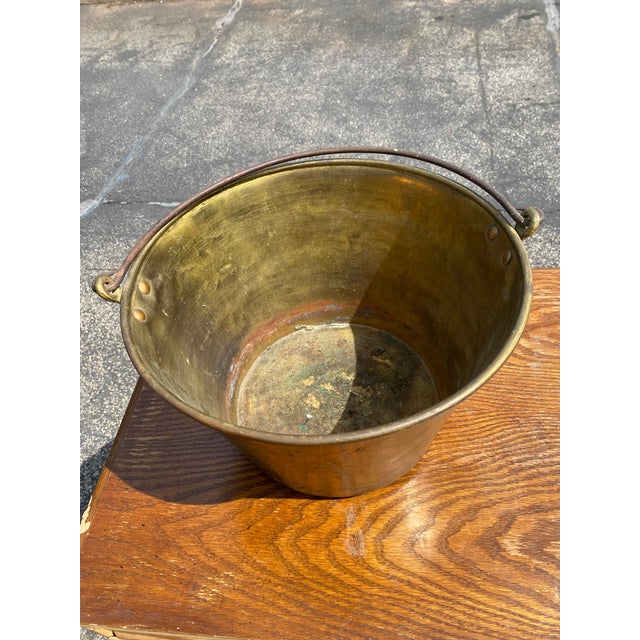 Antique spun brass bucket pail. Features an iron swing handle attached with original rivets/nails and a primitive patch...