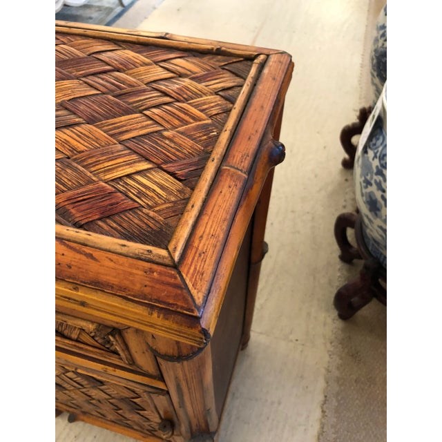 Handsome rattan wicker cabinet night stand with single drawer and door revealing storage within.