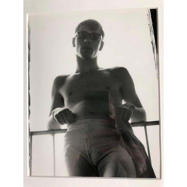 Black and white photograph of male figure on fire escape. Framed and matted under glass.
