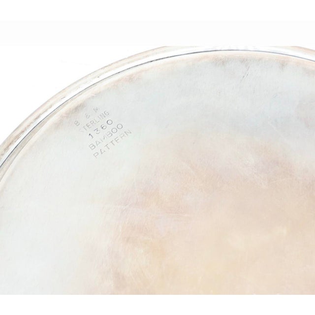 Elegant vintage sterling silver round tray by B&M Silver Co., designed with a sculptural bamboo-pattern border. The raised...