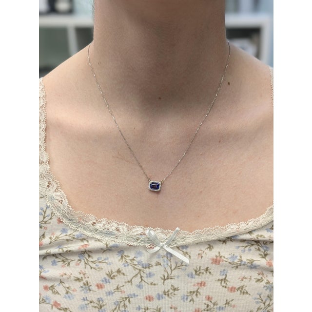 This timeless pendant necklace features a 0.97ct emerald-cut AAA tanzanite (7x5mm) with rich violet-blue hues, expertly...