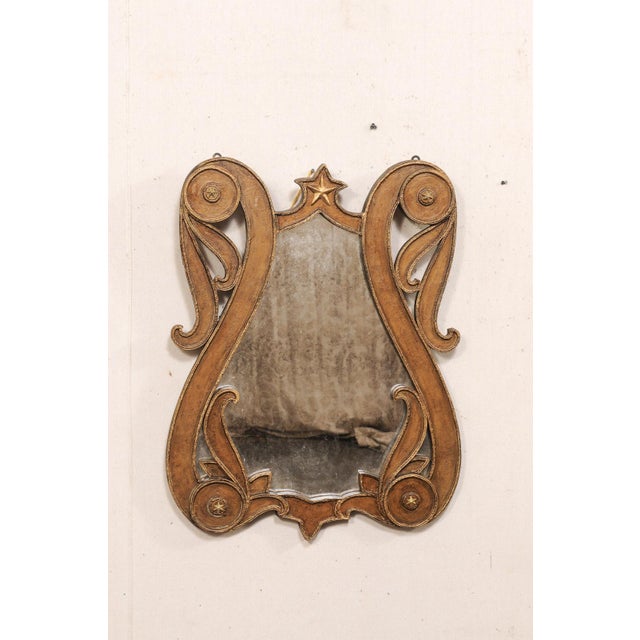 An Italian unusual lyre-shaped mirror with star accents. This vintage mirror from Italy has a curvy, lyre-shaped body with...
