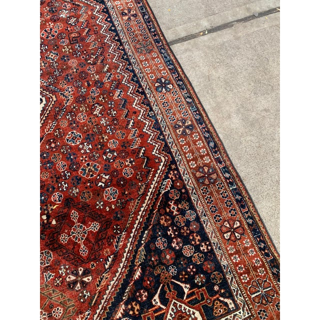 This handmade antique Persian Qashqai rug from the early 1900s is a stunning example of traditional tribal weaving....