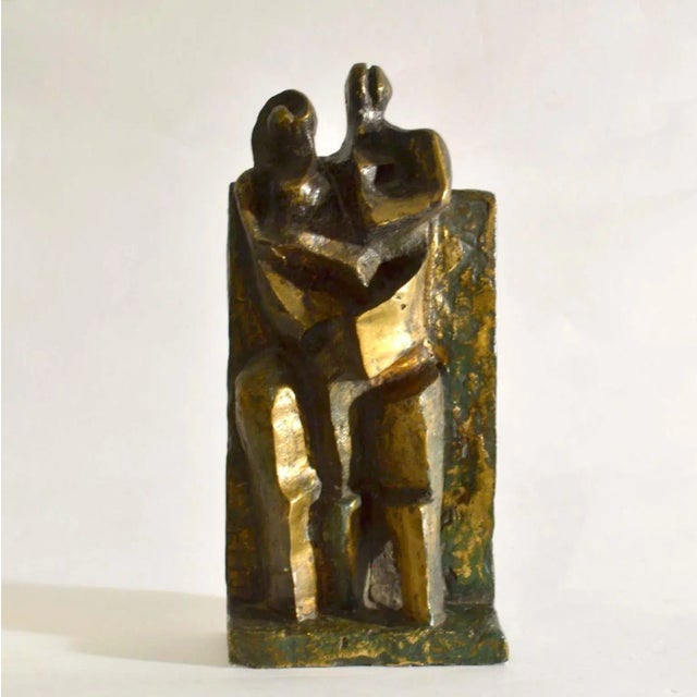 Cubist bronze sculpture of a standing couple with child is framed by a rectangular wall which continues into the base acts...