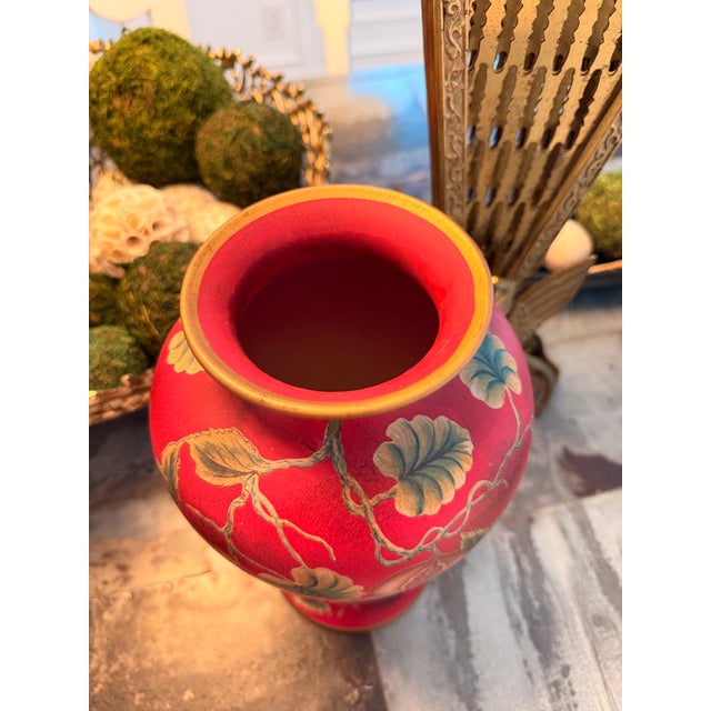 Decorative hand-painted chinoiserie-style vase featuring an elegant crimson red background accented with birds,...