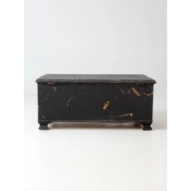 An early 20th-century trunk wrapped in black woven canvas with the look of wicker. The softly aged surface lends warmth...