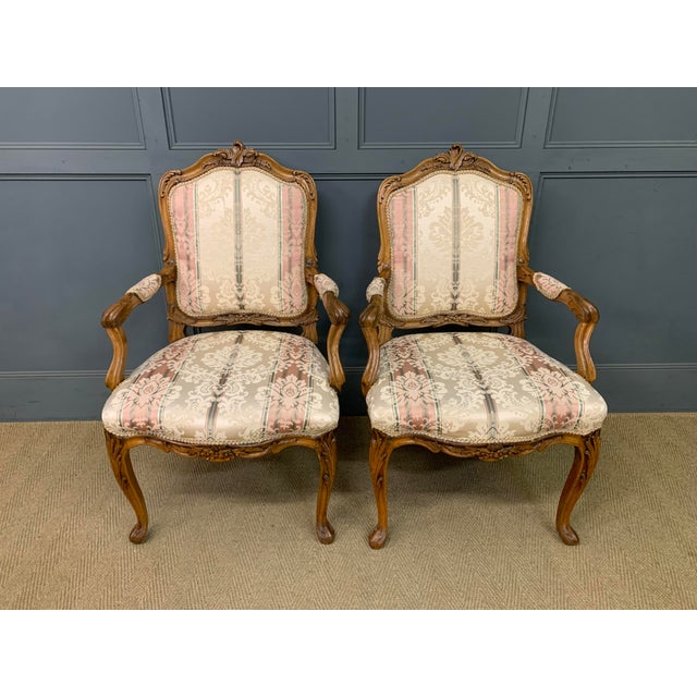A charming pair of early 20th century French walnut armchairs, or fauteuils. Well constructed in solid walnut and...