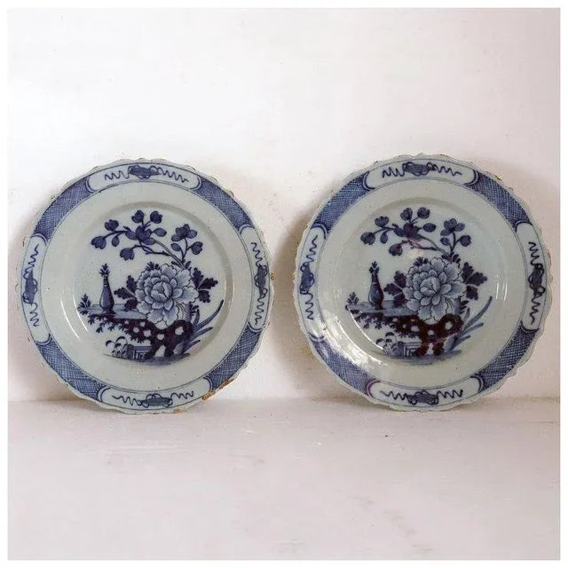 DETAILS A pair of antique tin-glazed earthenware plates with a Chinese style floral garden landscape. Of round form with a...
