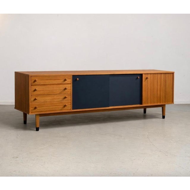 Light wood sideboard with contrasting sliding black panels. 4 drawers on the left part.