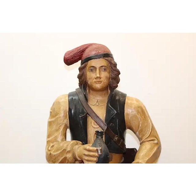 This nearly 44-inch-tall, solid wood sculpture of a handsome traveler imbibing atop a barrel is Swiss or German. It calls...