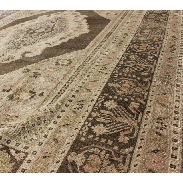 Measures: 6'1 x 9'8 Set on a green background and border, this vintage Turkish Oushak displays a diamond medallion...