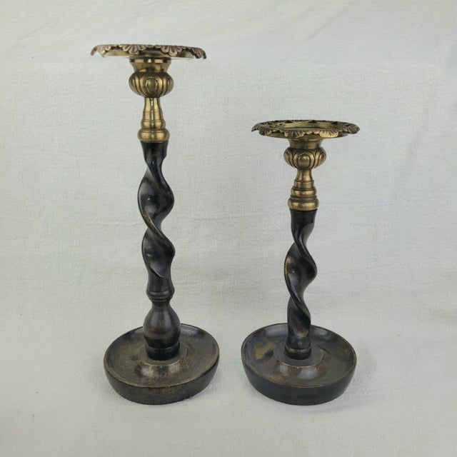 Vintage brass and bronze candlestick holders feature a striking barley twist stem design with ornate scalloped drip pans....