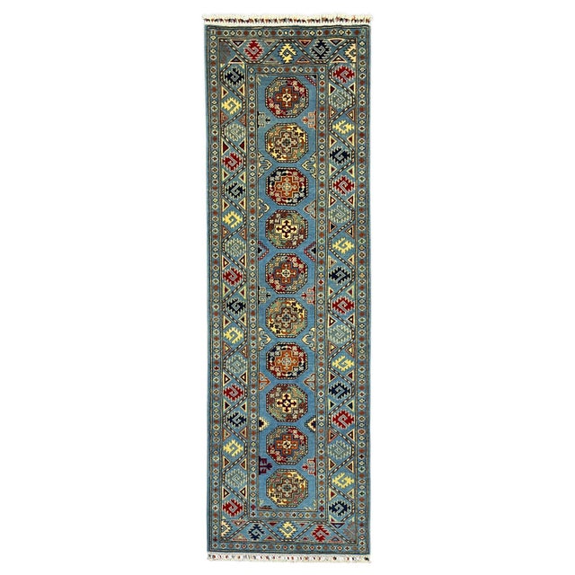 This natural dye wool runner has a blue field with a row of repeating octagonal gul motifs in burgundy, rust, cream, and...