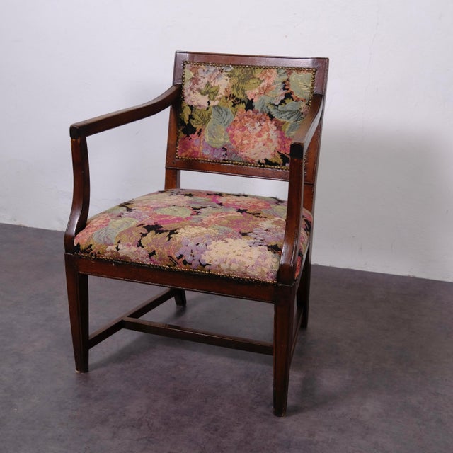 This antique chair or armchair with cushion is crafted from dark solid wood and embellished with a tapestry fabric...