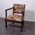 This antique chair or armchair with cushion is crafted from dark solid wood and embellished with a tapestry fabric...