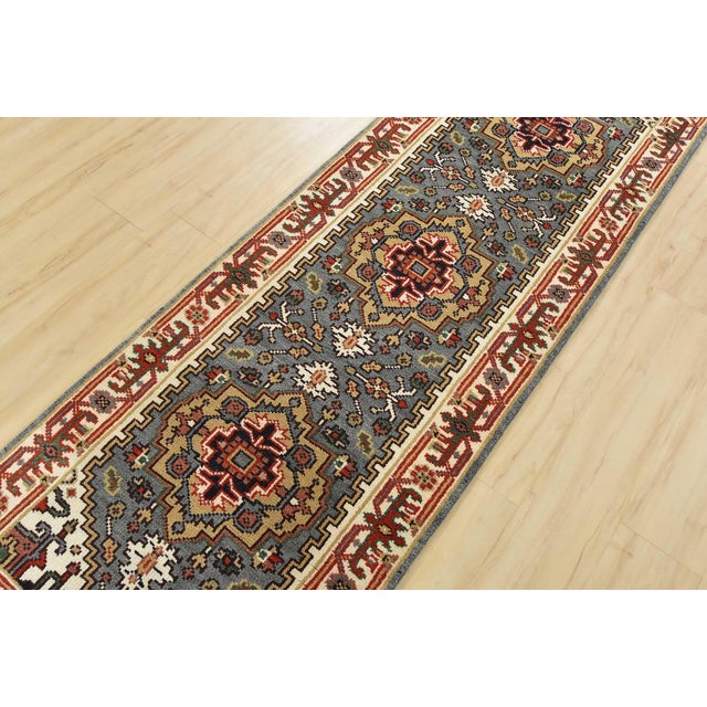 A traditional tribal Heriz runner hand-knotted with an all-wool pile on a cotton foundation. This oriental rug features...