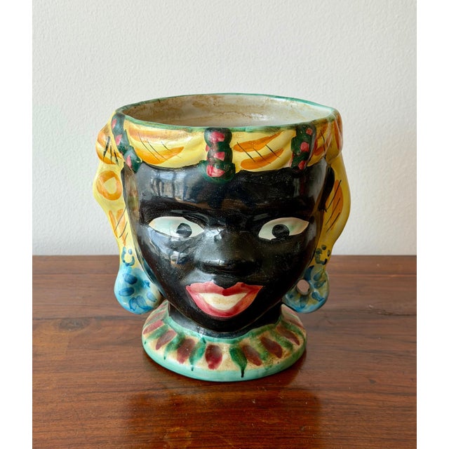 A vividly glazed mid-century ceramic head planter with expressive hand-painted detailing and a warm, sun-washed palette....