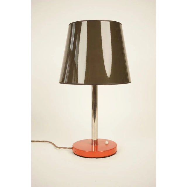 A simple elegant table lamp from the 1930s. Made up of a painted orange base and a chrome extension, the lamp supports a...