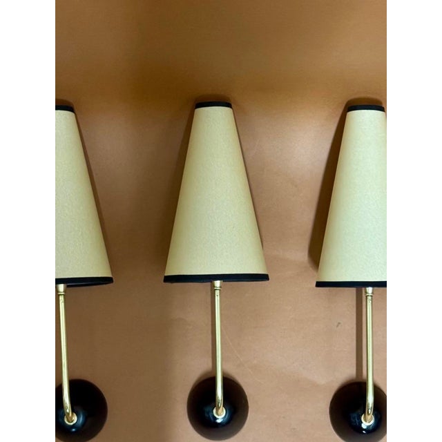 Jean Royere style wall light, black lacquered brass with beige paper lampshade This piece is attributed to the mentioned...