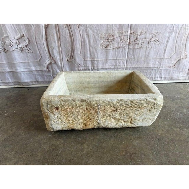 A beautifully hand-carved antique stone sink basin featuring substantial proportions, primitive craftsmanship, and...