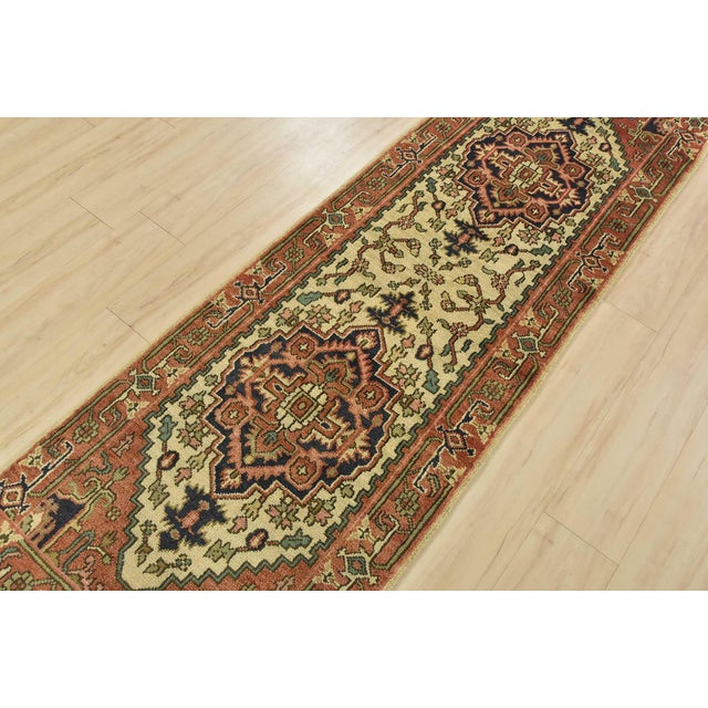 A traditional tribal Heriz runner hand-knotted with an all-wool pile on a cotton foundation. This oriental rug features...