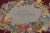 This antique 4x6 hooked rug, circa 1920–1929, features a vibrant fruit and floral wreath medallion set against a rich...