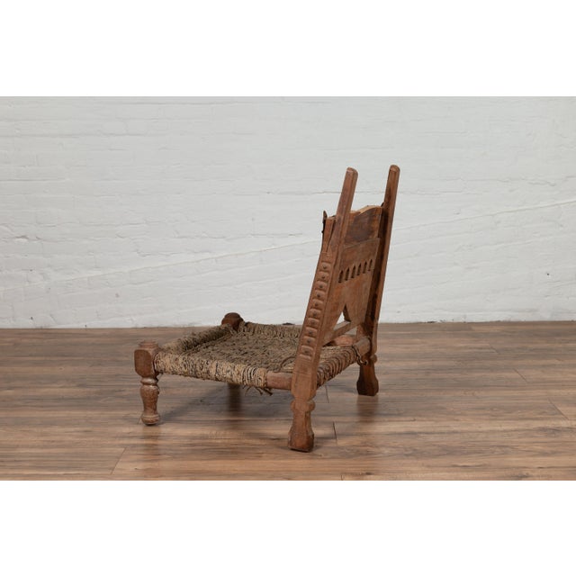 An antique Indian rustic low chair from the 19th century with rope accents and elephant motifs. Born in India during the...