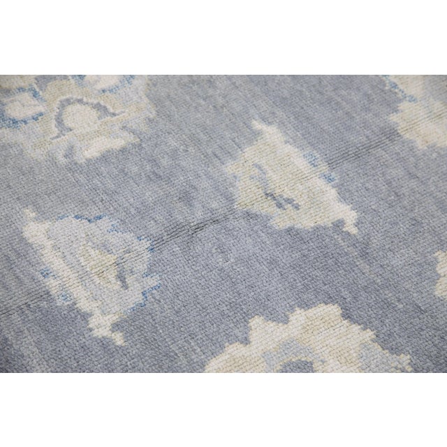 This modern Turkish Oushak rug is a stunning piece of art that has been handwoven using traditional techniques by skilled...