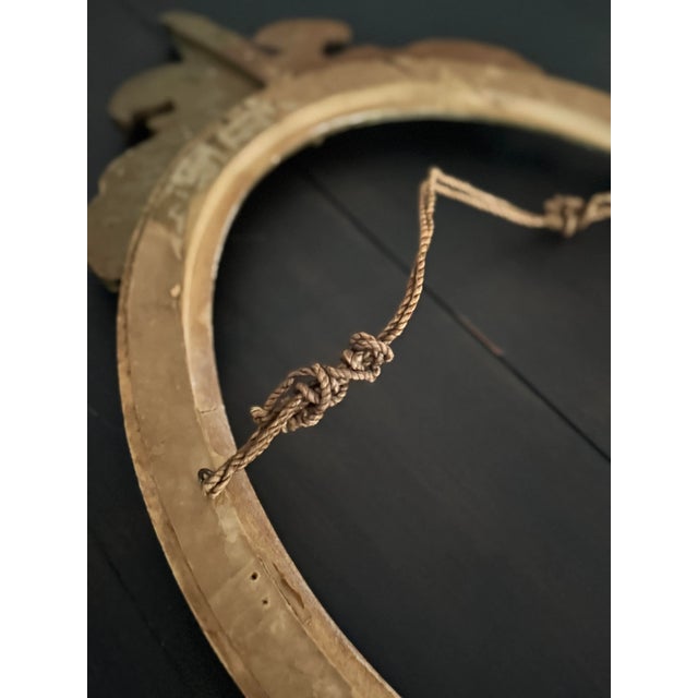 A graceful pair of early 1900s gilt frames, offered as a set. The oval frame features a detailed fleur-de-lis crest...