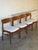 This set of four dining chairs features gently curved teak backrests and clean architectural frames. Their open silhouette...