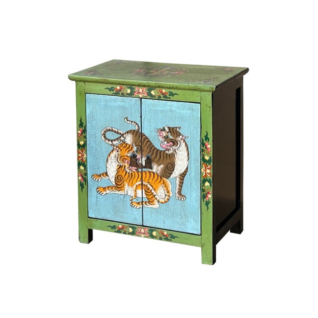 This striking, hand-painted wooden cabinet features a vibrant folk-art aesthetic, characterized by a bold palette of lime...