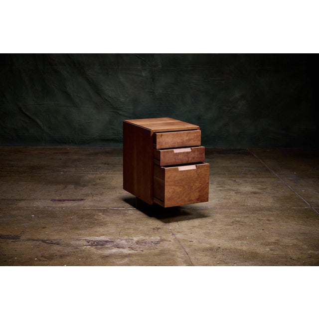 George Nakashima three-drawer pedestal in solid wood, a Mid Century Modern cabinet with integrated carved pulls and a...