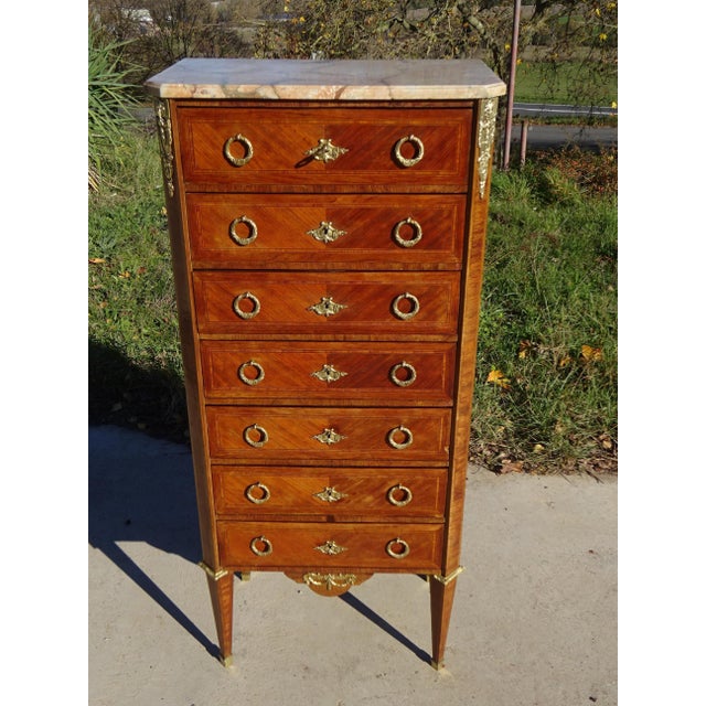 Antique seven-drawer chest, traditionally made in France in the 19th century. Beautiful marquetry of various woods adorns...