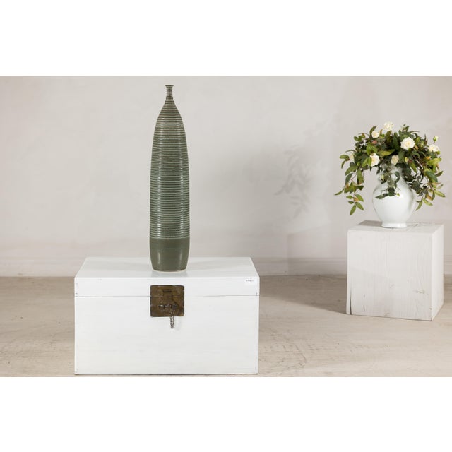 This tall artisan ceramic vase presents a striking, architectural silhouette, rising to an impressive 31 inches in height....