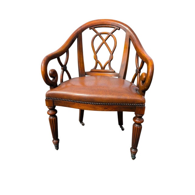 A handsome pair of traditional-style walnut-finished armchairs with warm brown leather seats, decorative nailhead trim,...