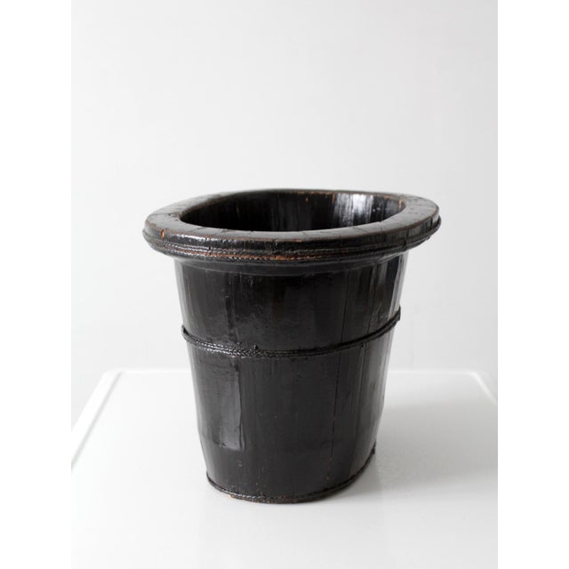An antique Chinese coopered wood basin featuring a black lacquer finish, thick flared rim, and hand-carved braided bands....