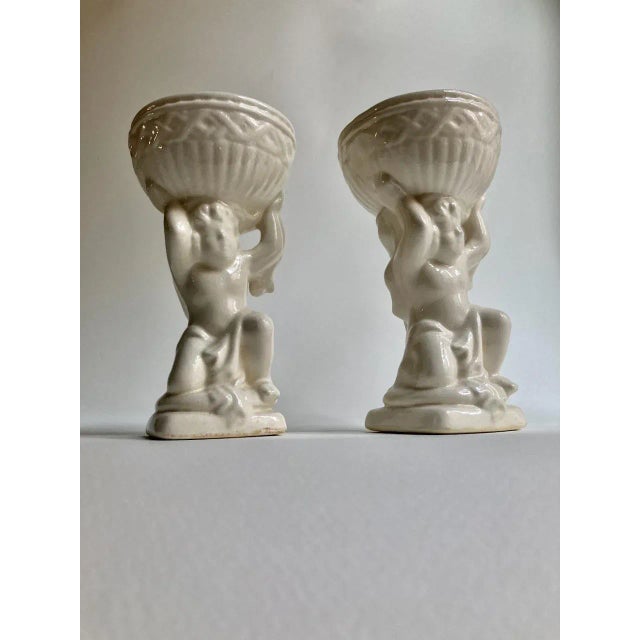 Pair of draped and kneeling Off White Glazed Ceramic Putti's and holding adorned Bowls on balanced squat square base....