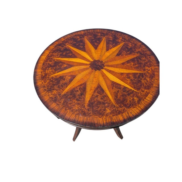 A distinctive vintage Uttermost round bistro table featuring a richly figured wood-veneer top centered by a dramatic...
