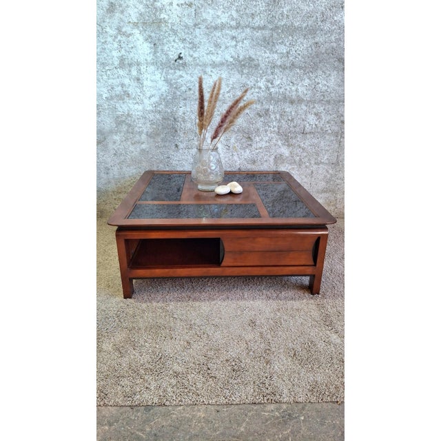Large square coffee table in solid mahogany/cherry stained wood, with a contemporary design dating from the 1990s. The...
