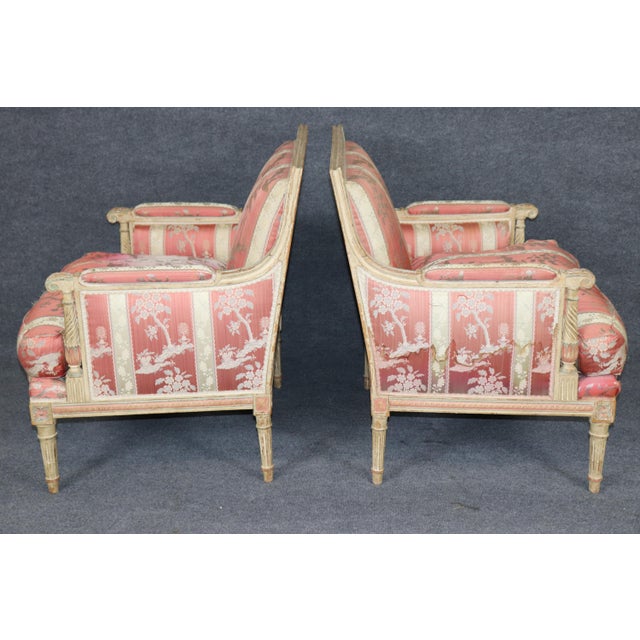 This elegant pair of French painted and parcel-gilt bergère armchairs, attributed to Maison Jansen and dating to the...
