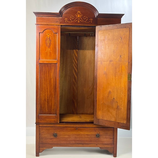 Edwardian-style inlaid mahogany wardrobe. This piece is beautifully adorned with intricate satinwood and fruitwood...