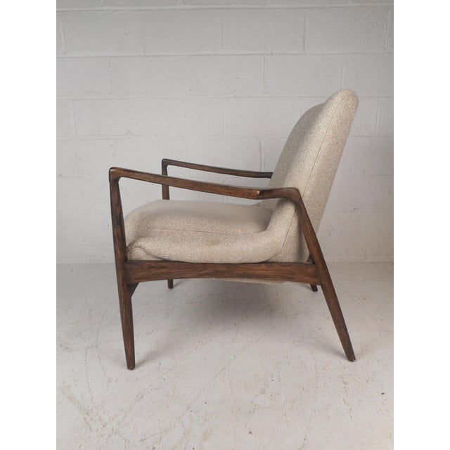 This gorgeous mid-century style lounge chair features a sculpted frame with angled back legs. The high back rest and...